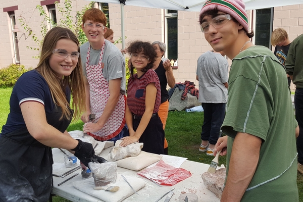 High school students doing stone carving outside