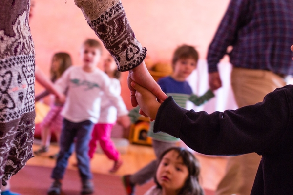 Young children playing behind a child and adult holding hands