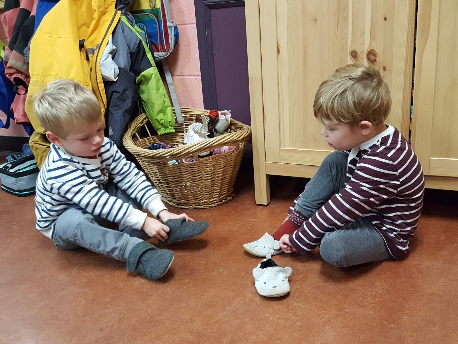 Two young boys putting on slippers