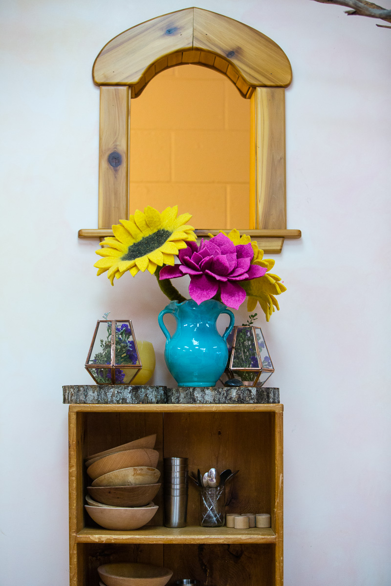Interior window felt flowers on shelf with small plates and cups