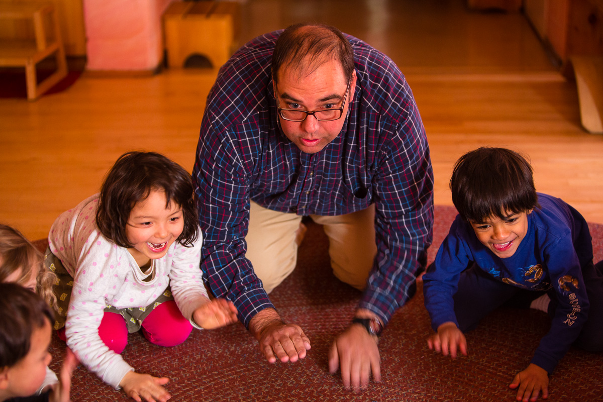 Teacher kneeling on ground with two young students