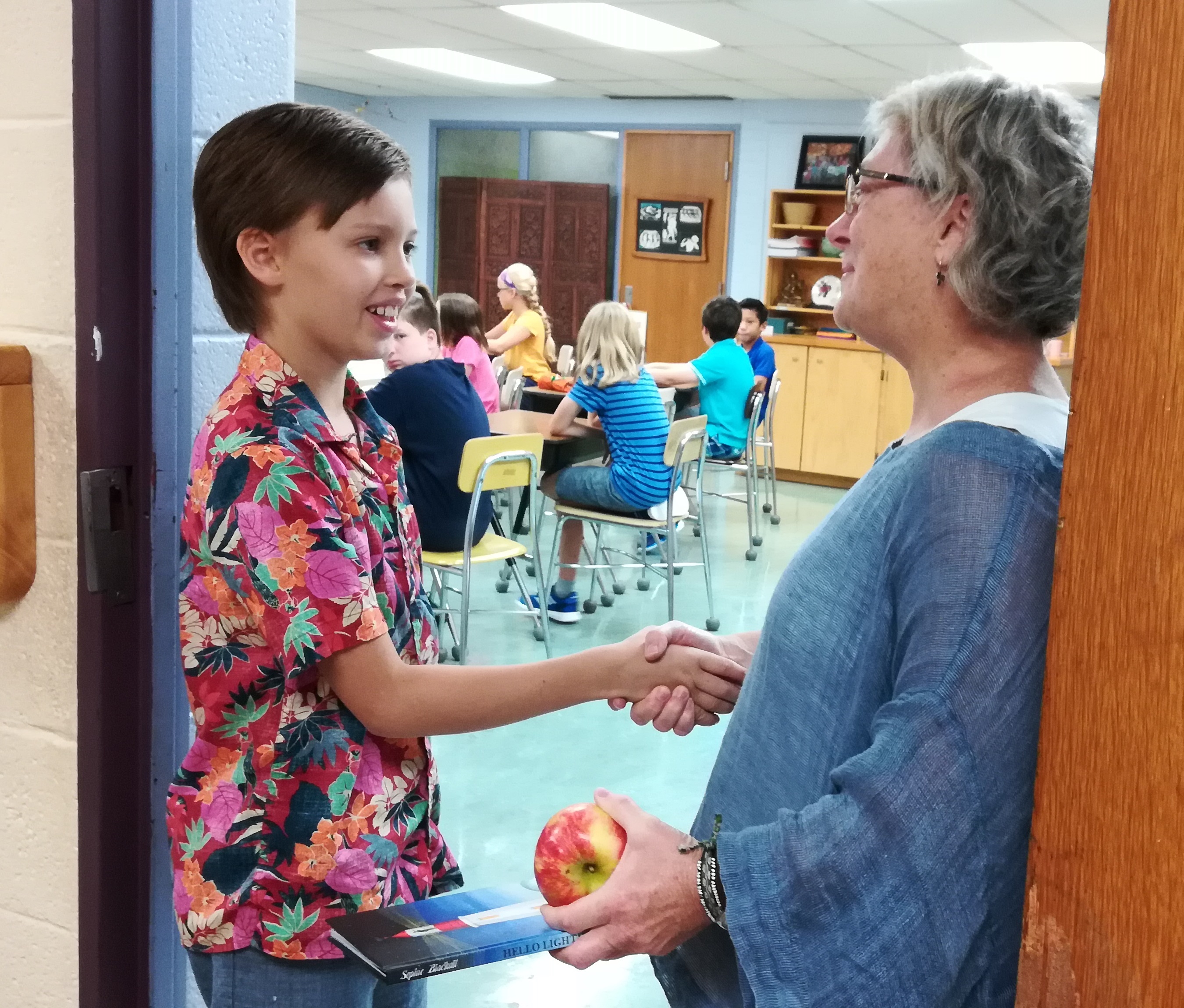 Teacher shaking hand of boy entering class