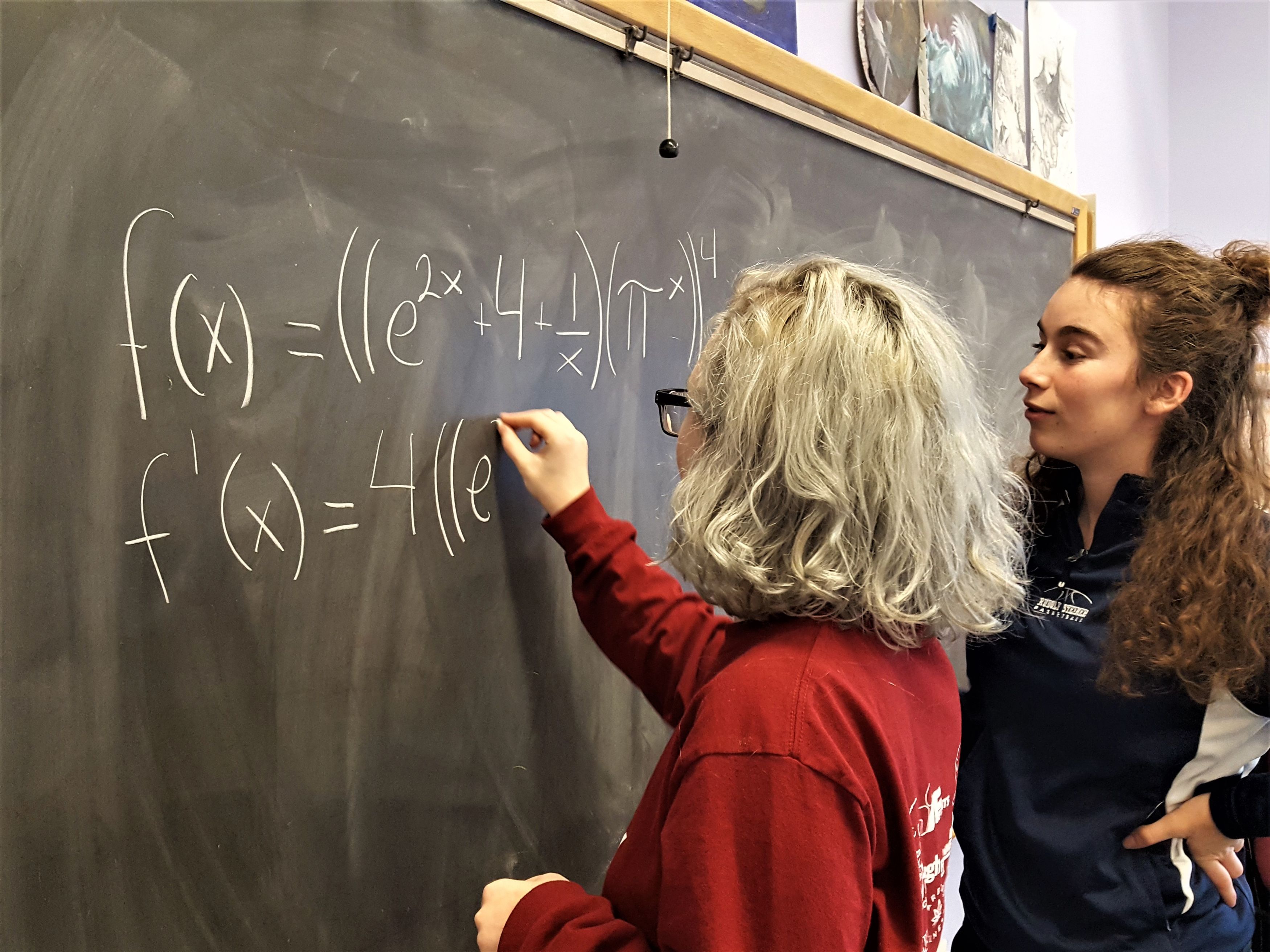Two girls at chalkboard doing math