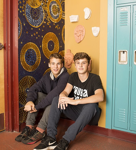 Two boys sitting next to lockers