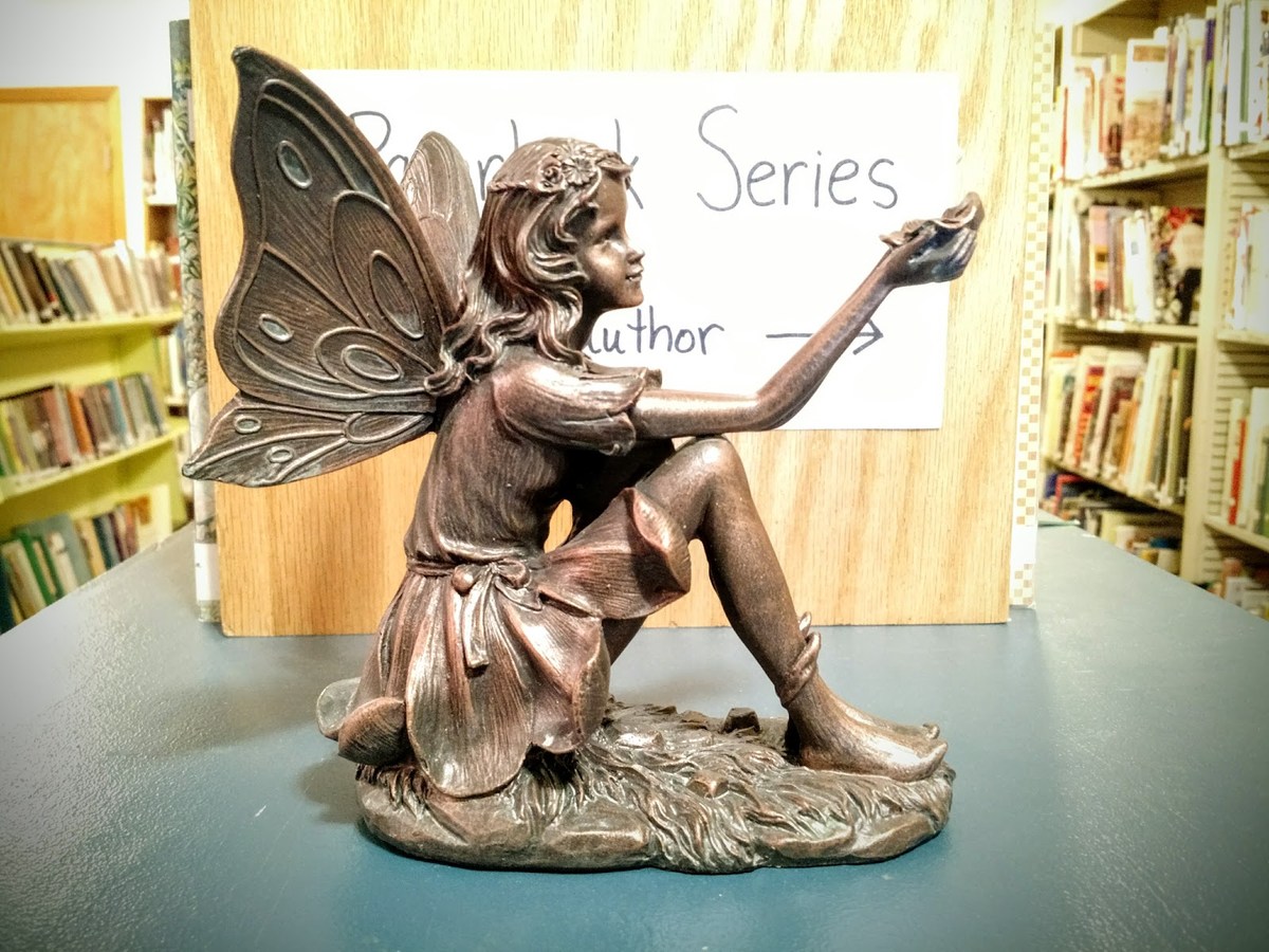 Brass Fairy Sculpture in Front of Bookshelf